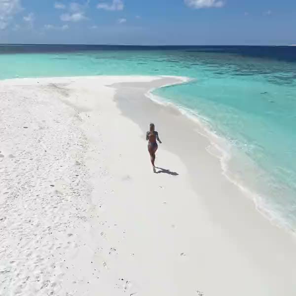 Walking out along an empty sandbank where the water turns deep blue