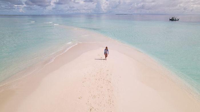 A lone figure walking along an endless sandbank