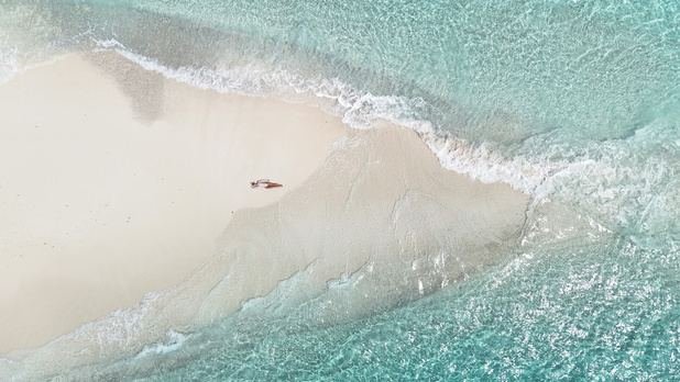 Aerial of waves washing over a sandbank