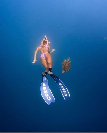 Freediver descending into deep blue water