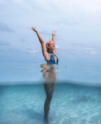 Woman waving with one arm up in turquoise shallows