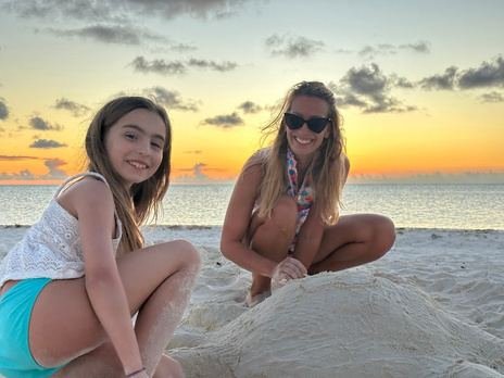 Two friends sitting on a sandbank at sunset