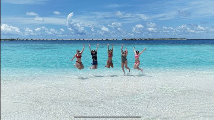 Group jumping in the shallows in front of a sandbank